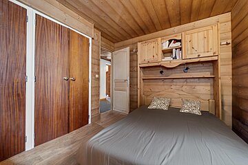 A bedroom with a bed and a bookshelf above it