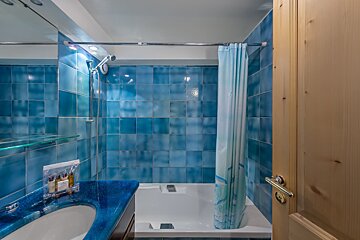 A bathroom with blue tiles and a bathtub