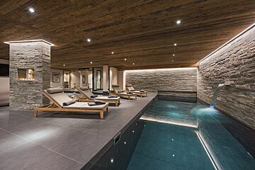 A swimming pool with a waterfall and lounge chairs