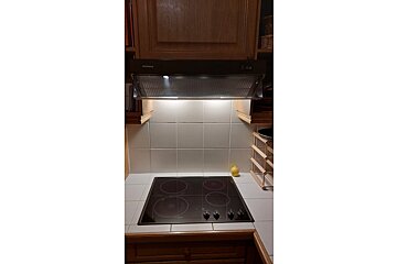 A stove top with a bosch hood above it