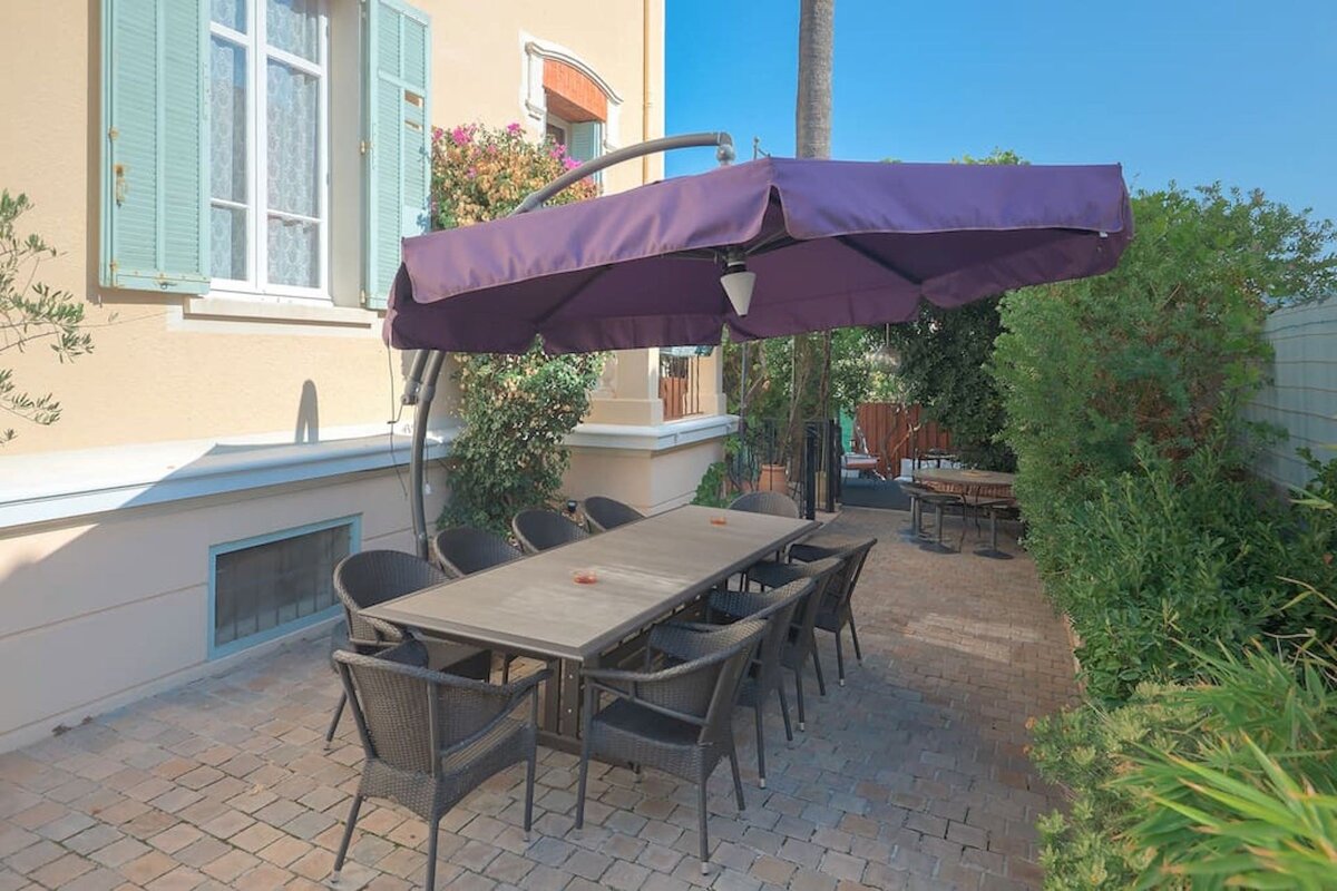 A patio with a table and chairs under a purple umbrella