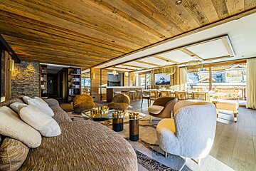 A living room with a brown couch and white chairs