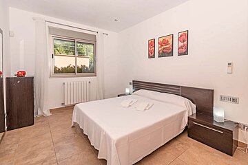 A bedroom with a bed and three paintings on the wall