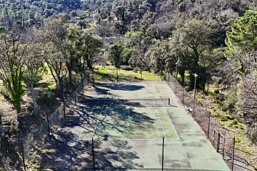 An aerial view of a tennis court surrounded by trees
