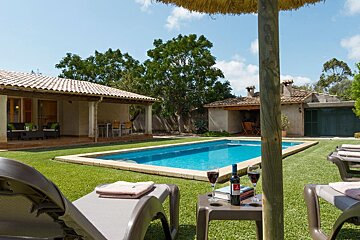 A bottle of wine sits on a table in front of a swimming pool