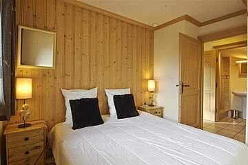 A bedroom with wood paneling and a bed with black pillows