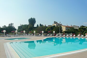 A large swimming pool surrounded by chairs and umbrellas