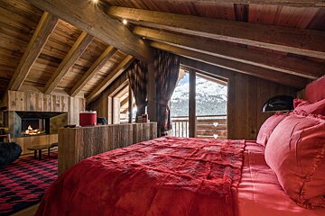 A bedroom with a red bed and a fireplace