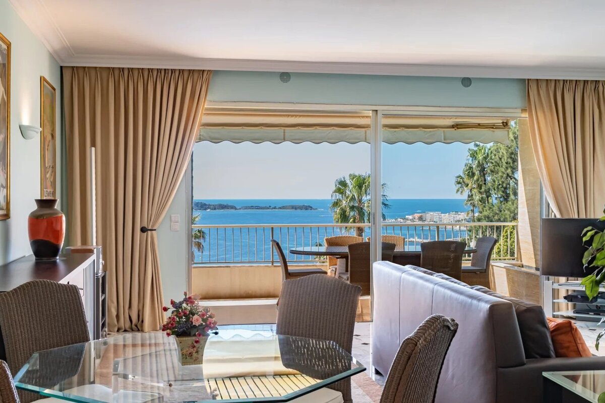 Bright apartment interior featuring a dining area opening onto a balcony with stunning ocean views.