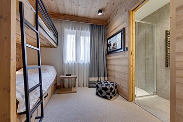 A bedroom with bunk beds and a television on the wall