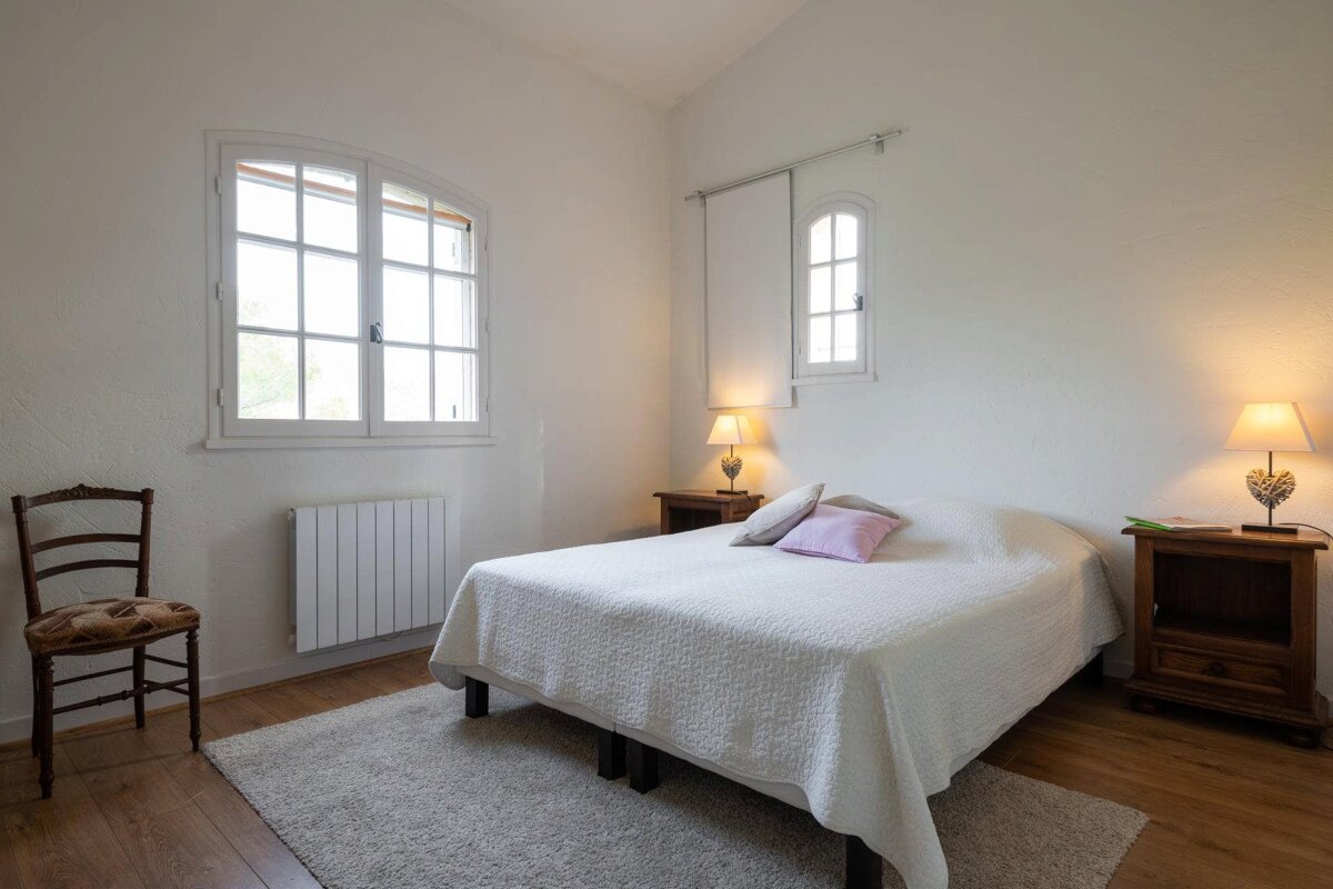 A bedroom with a bed a chair and two lamps