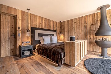 A bedroom with wood paneled walls and a fireplace
