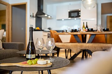 A bottle of champagne sits on a table next to two wine glasses