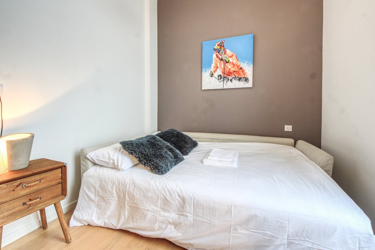 A bed with a painting on the wall above it