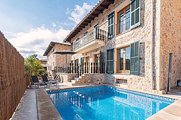 A large stone house with a swimming pool in front of it