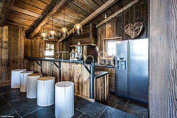 A kitchen with wooden walls and a stainless steel refrigerator