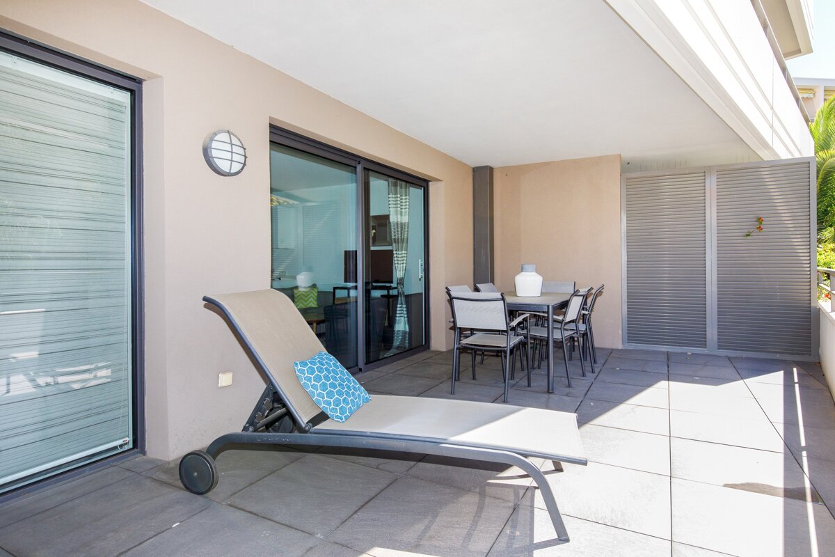 A patio with a table and chairs and a lounge chair