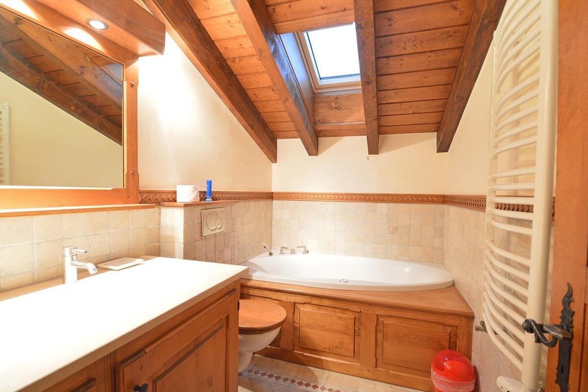 A bathroom with a tub and a skylight above it
