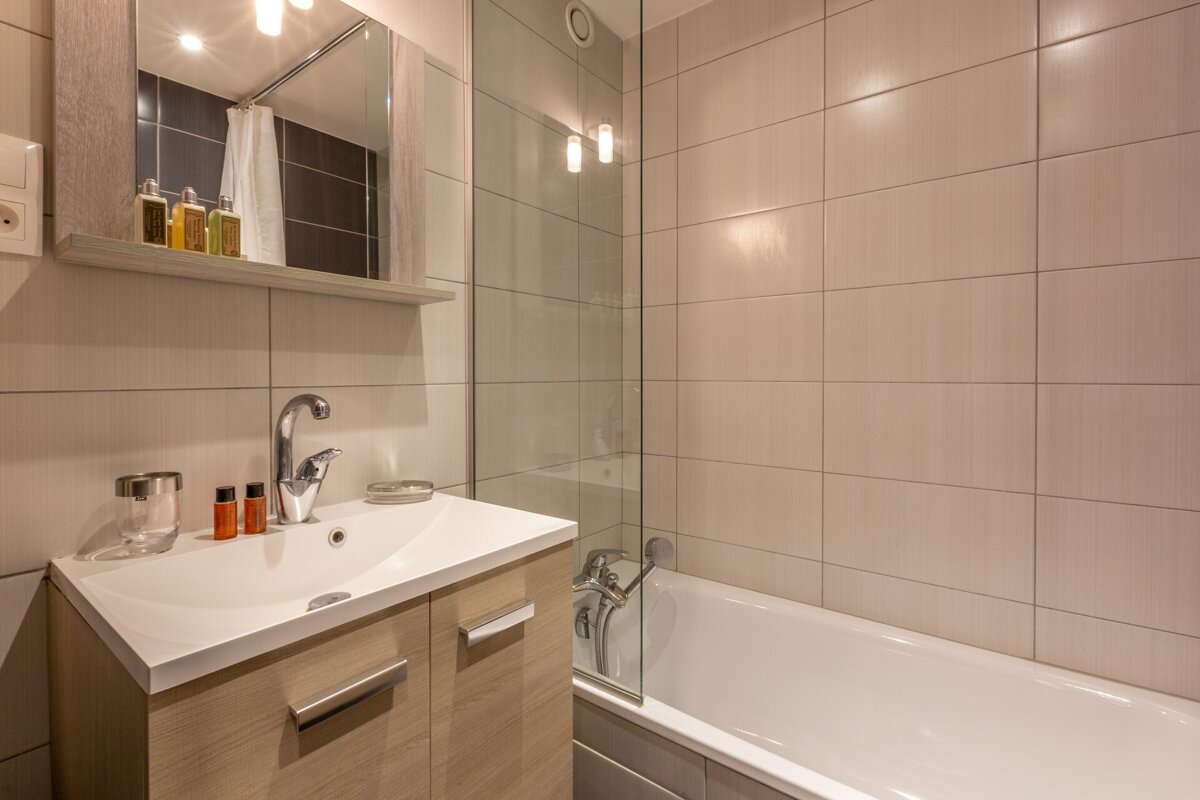 A bunk bed in a bathroom next to a bathtub