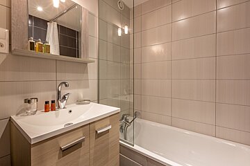 A bunk bed in a bathroom next to a bathtub