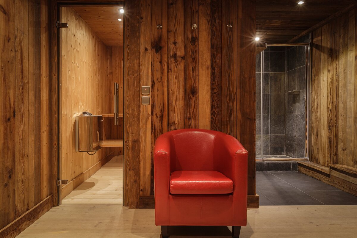 A red leather chair in a wooden room next to a shower
