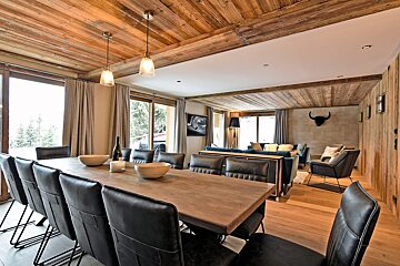 A dining room with a long table and black chairs