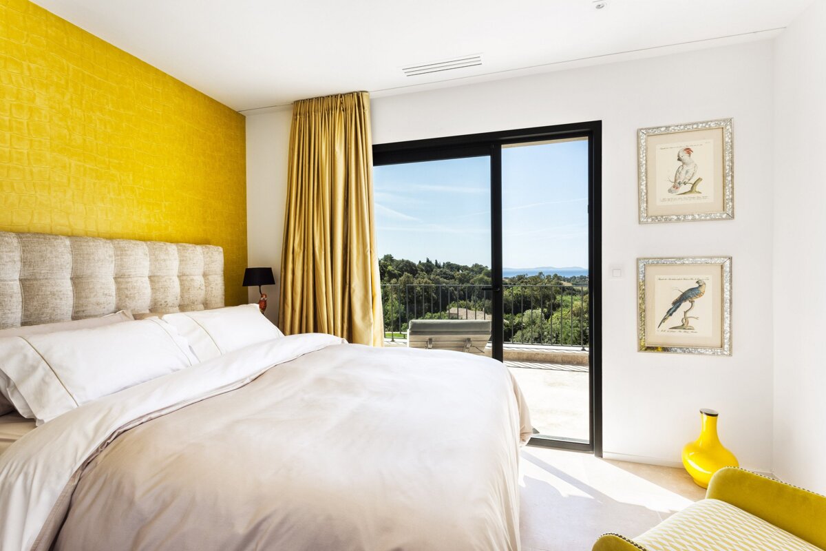 A bedroom with yellow walls and a large bed