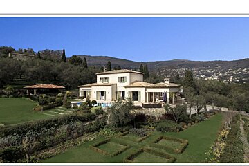 A large house sits on top of a lush green hillside