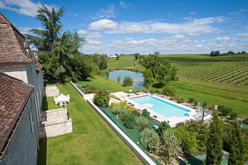 A large swimming pool is surrounded by a lush green field