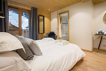 A bedroom with a large bed and a chair