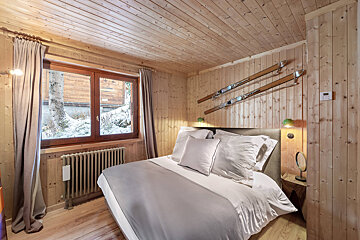 A bedroom with a bed and two skis on the wall