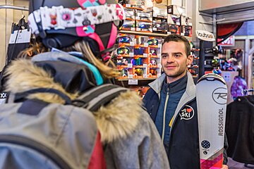 A man holding a pair of skis that say rossignol
