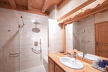 A bathroom with two sinks and a walk in shower