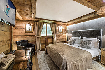 A bedroom with a large bed and a flat screen tv