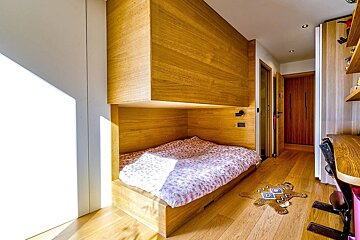 Modern wooden bedroom featuring a built-in alcove bed, hardwood floors, and bright sunlight.