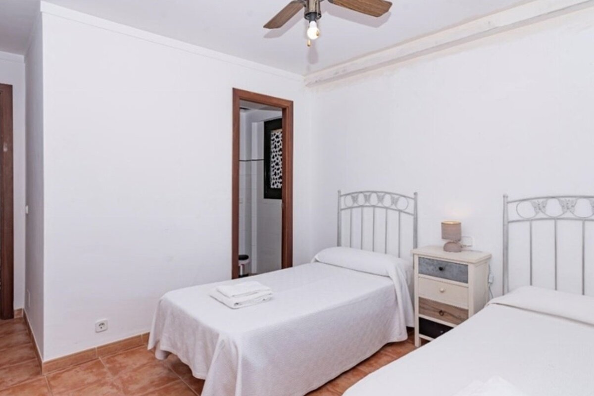 A bedroom with two beds and a ceiling fan