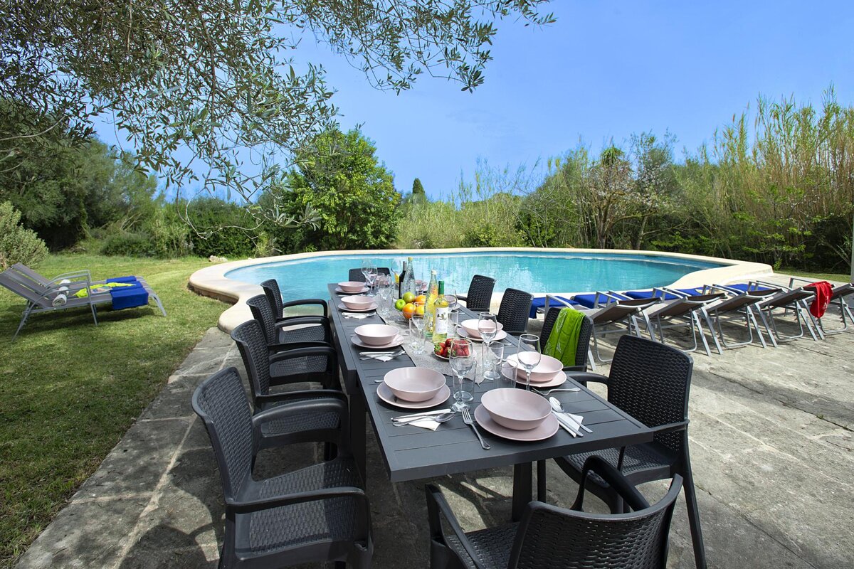 A table with plates and glasses on it in front of a pool