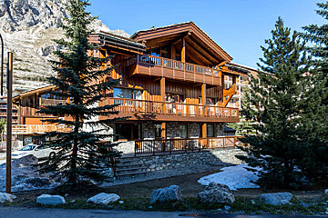 A large wooden house with a stone wall and balconies