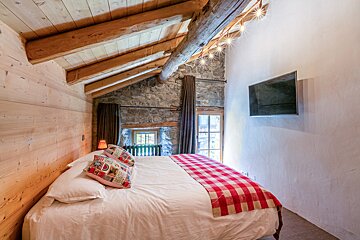 A bedroom with a bed and a television on the wall