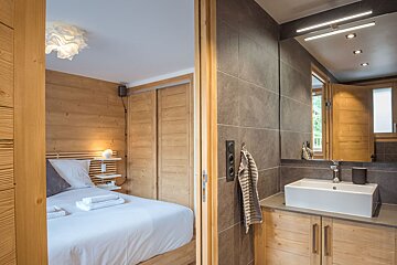 A bedroom with a bed and a bathroom with a sink