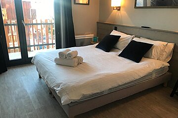 A hotel room with a large bed and a balcony