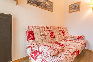 A red and white couch with a pattern of hearts and flowers