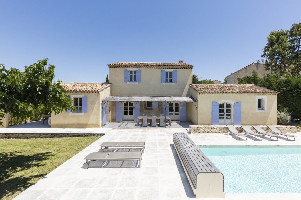 A house with blue shutters sits next to a swimming pool
