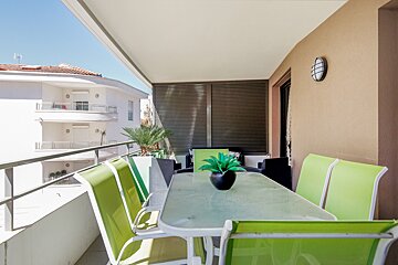 A balcony with green chairs and a table with a plant on it