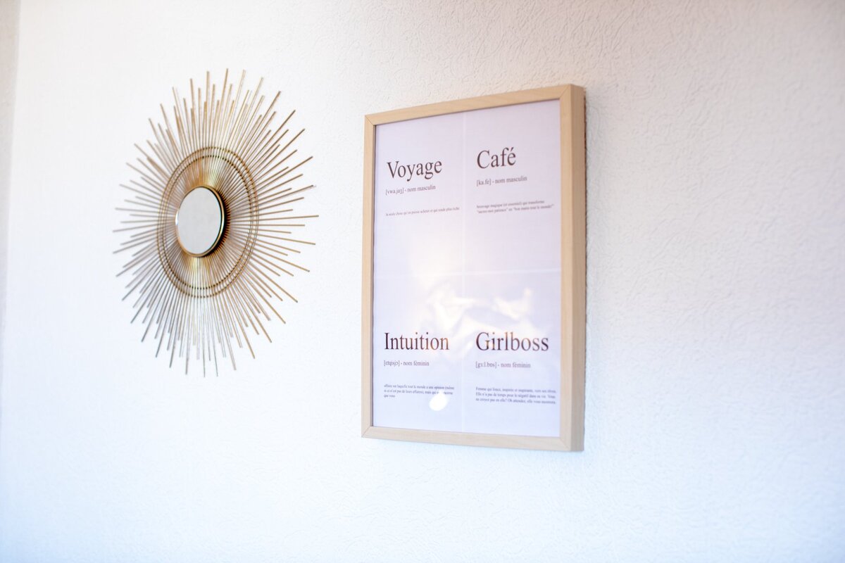A framed poster on a wall that says voyage cafe intuition and girlboss