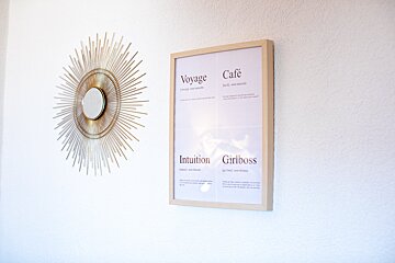 A framed poster on a wall that says voyage cafe intuition and girlboss