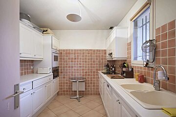 A kitchen with white cabinets and pink tile walls