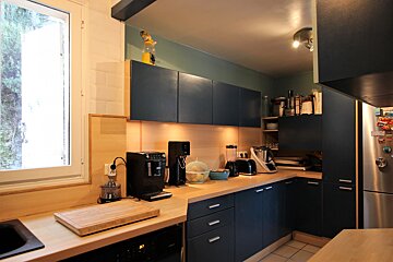 A kitchen with blue cabinets and a cutting board on the counter