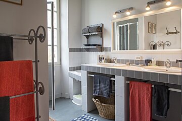 A bathroom with two sinks and a basket on the floor