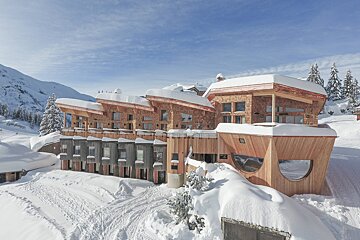 A large wooden building covered in snow with a blue sky in the background